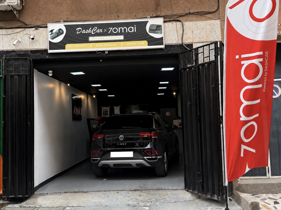 Façade du showroom DashCar à Casablanca : enseigne « DashCar × 70mai — Drive Safe, Drive Smart », rideau ouvert et véhicule à l'intérieur du magasin
